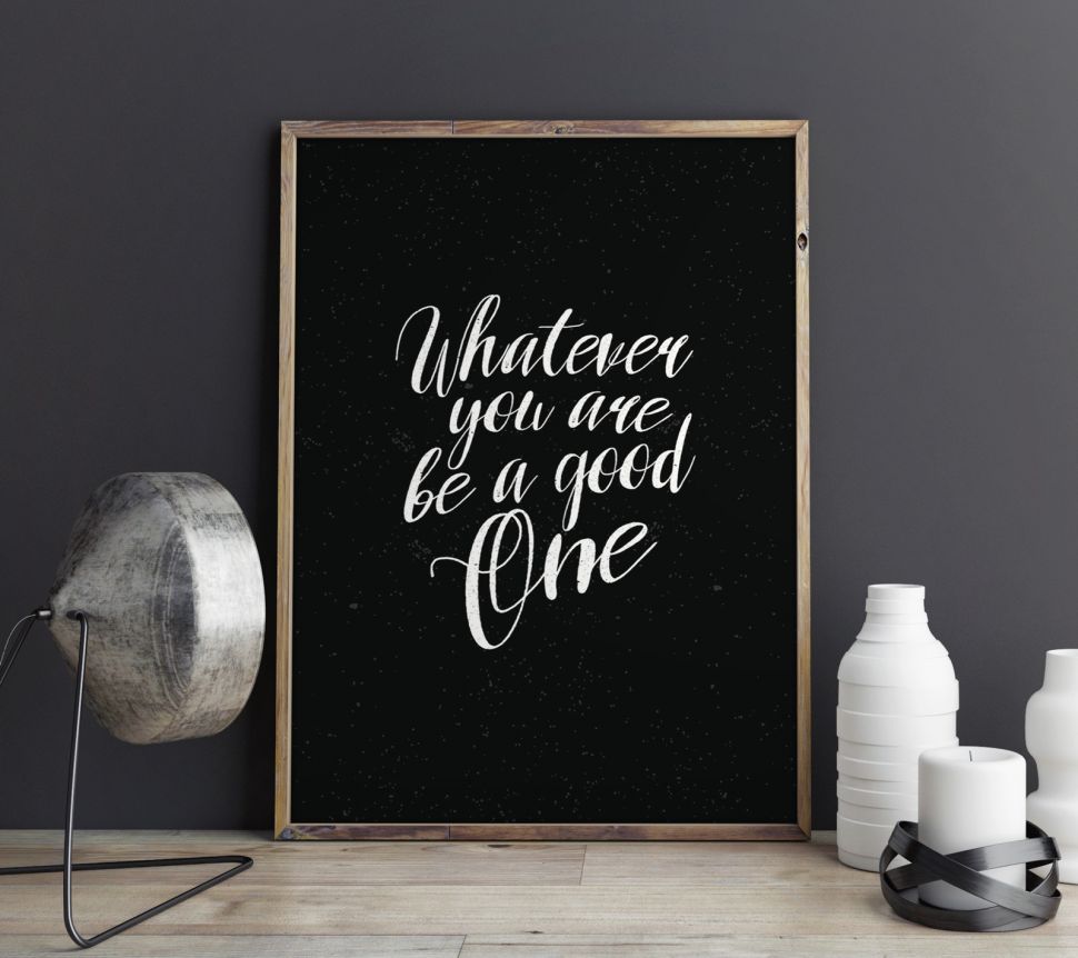 Plakat stojący na biurku oprawiony w ramę przedstawiający napis ''Whatever you are be a good one''