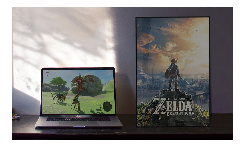Pokój gracza z plakatem z gry The Legend Of Zelda leżącym w ramce na biurku