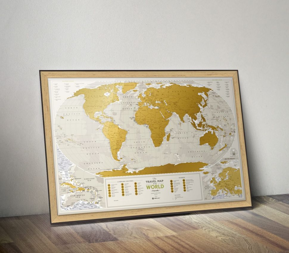 Złota mapa zdrapka Geography World stojąca na drewnianej podłodze