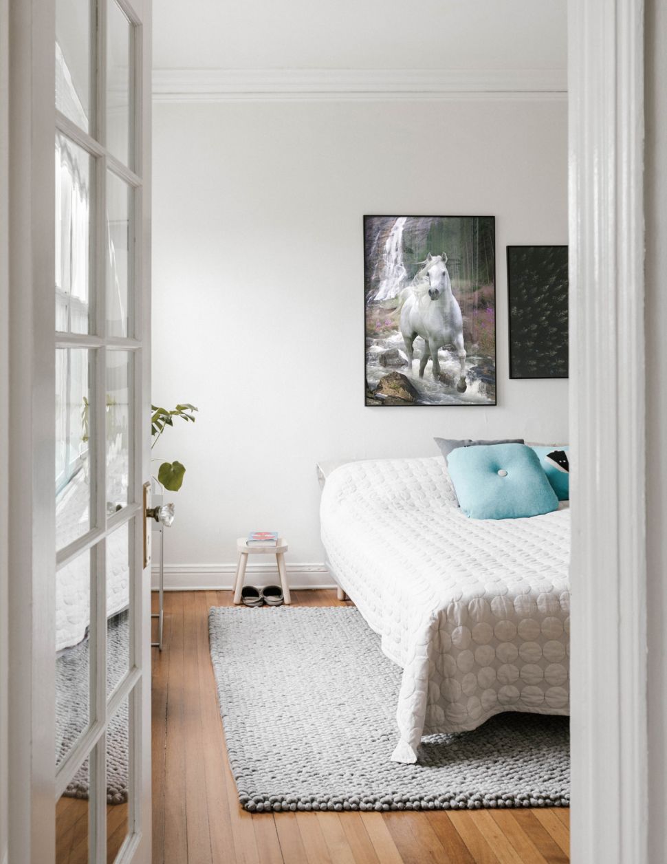 Plakat przedstawiający białego galopującego rumaka wiszący w sypialni nad łóżkiem