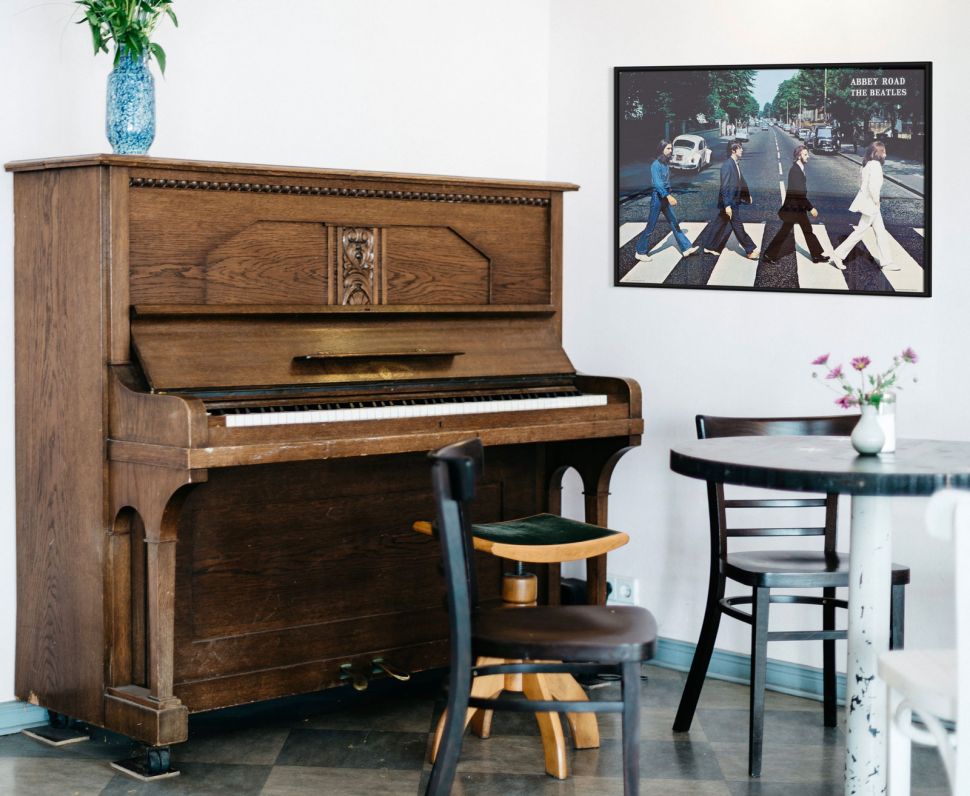 Plakat z zespołem The Beatles z słynnego Abbey Road wiszący na białej ścianie nad pianinem