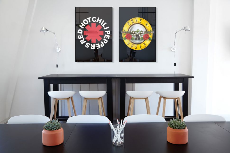 Plakat na ścianę z logo zespołu Guns N Roses wiszący w biurze nad czarnym biurkiem