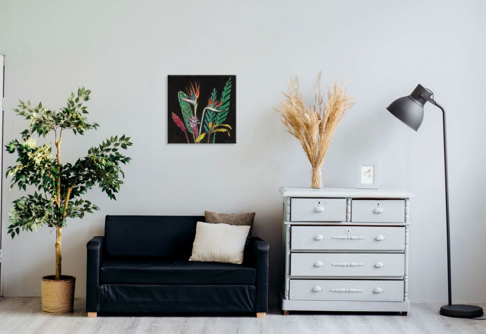 Obraz na płótnie z kolorowymi roślinami powieszony na białej ścianie nad czarną kanapą