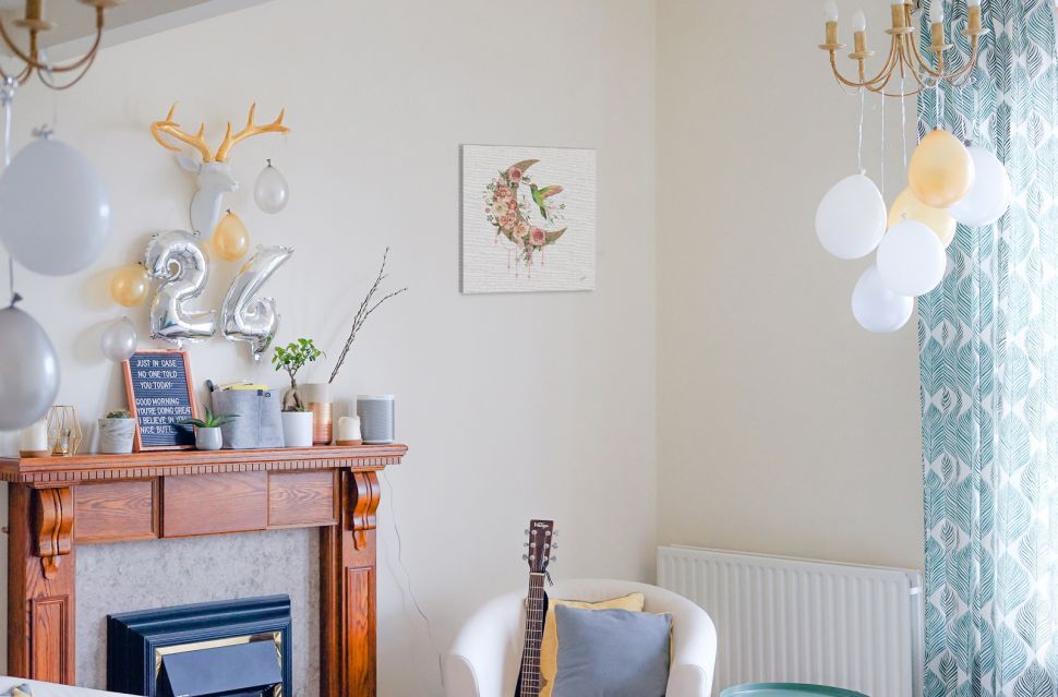 Canvas z księżycem w kwiatki i kolibrem wiszący w salonie na białej ścianie nad fotelem