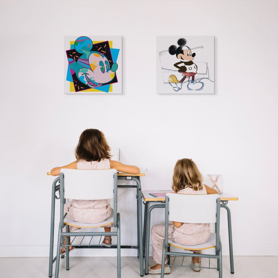 Obraz na płótnie z kolorową Myszką Miki powieszony na białej ścianie nad biurkami dla dzieci