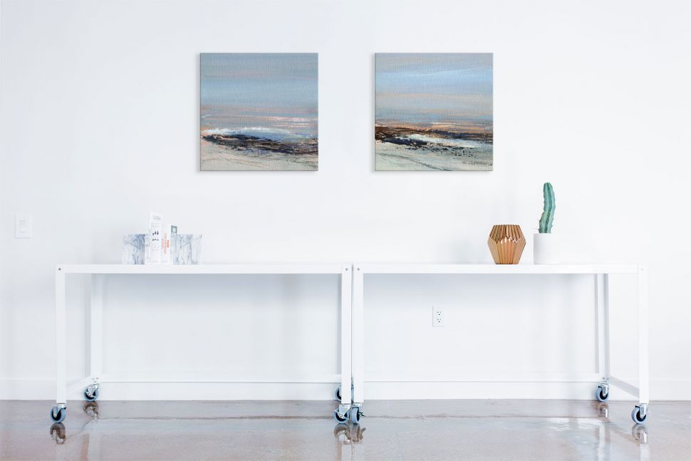Obrazy na płótnie namalowane przez Joanne Last powieszone nad stolikami na białej ścianie