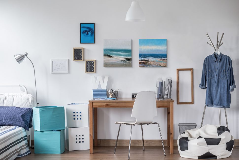 Canvasy z morskim krajobrazem powieszone w sypialni nad drewnianym biurkiem