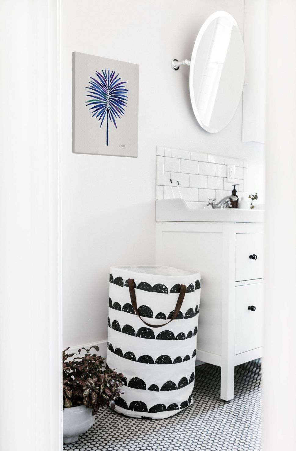 Canvas z liściem w kolorze indygo wiszący w łazience nad koszem do prania