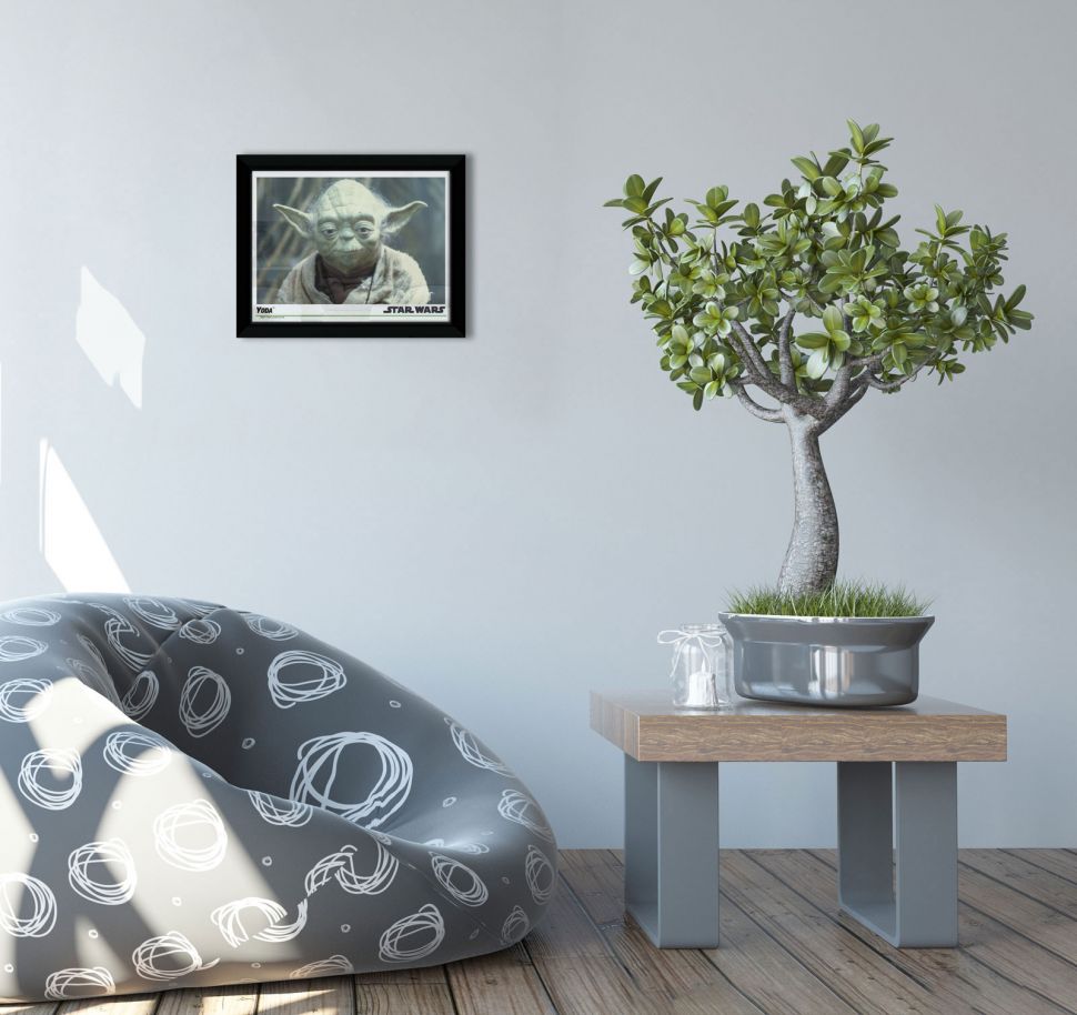 Obraz w czarnej ramie przedstawiający Yodę ze Star Wars wiszący na białej ścianie nad fotelem