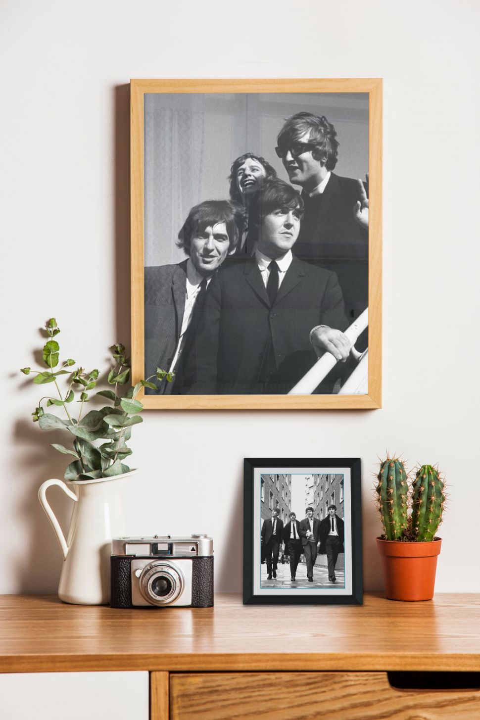 Obraz w czarnej ramie z zespołem The Beatles w Londynie postawiony na drewnianym biurku