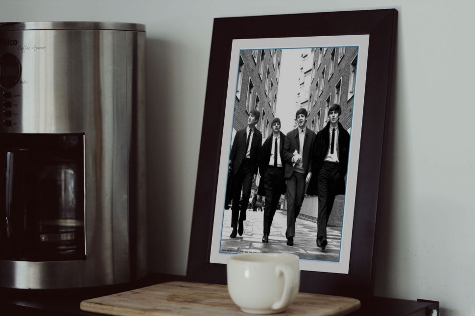 Obraz w ramie z członkami zespołu The Beatles postawiony w kuchni na blacie
