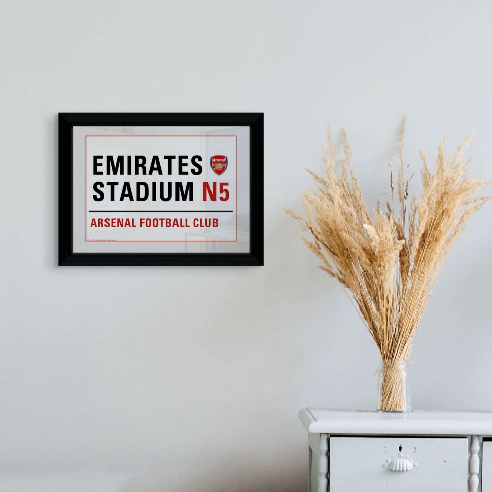 Obraz w ramce z napisem Emirates Stadium N5 Arsenal Football Club powieszony na białej ścianie