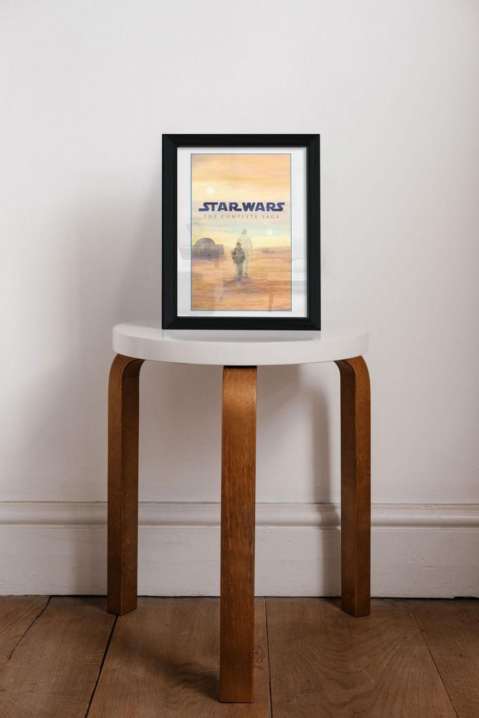 Obraz w czarnej ramce ze Star Wars postawiony na drewniano białym stoliku