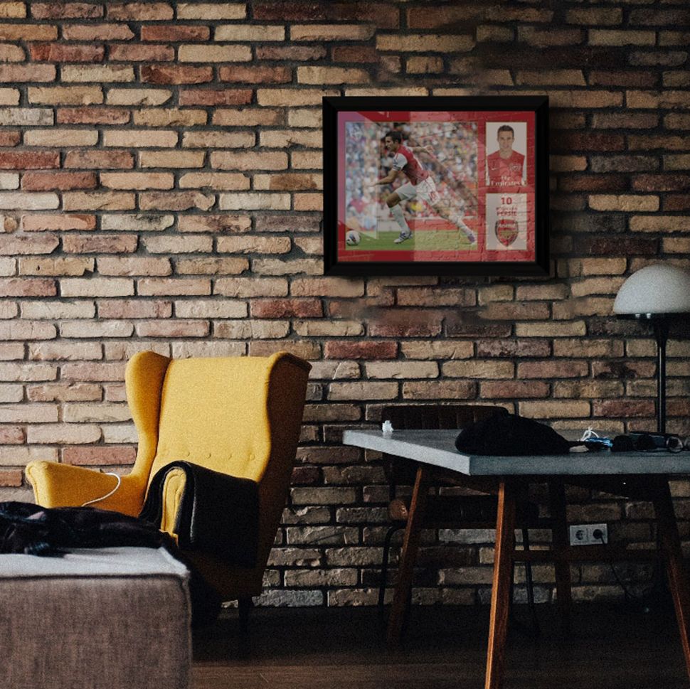 Obraz w ramce z zawodnikiem Arsenalu powieszony na ścianie z cegły w salonie