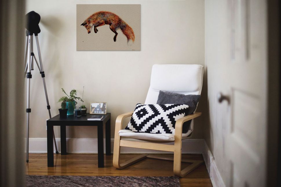 Obraz na płótnie z lisem polującym na osę powieszony nad ławą i fotelem wypoczynkowym