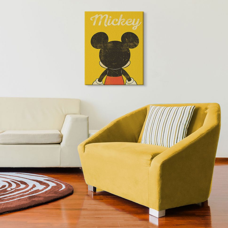 Obraz na płótnie z odwróconą Myszką Miki powieszony w salonie nad żółtą kanapą