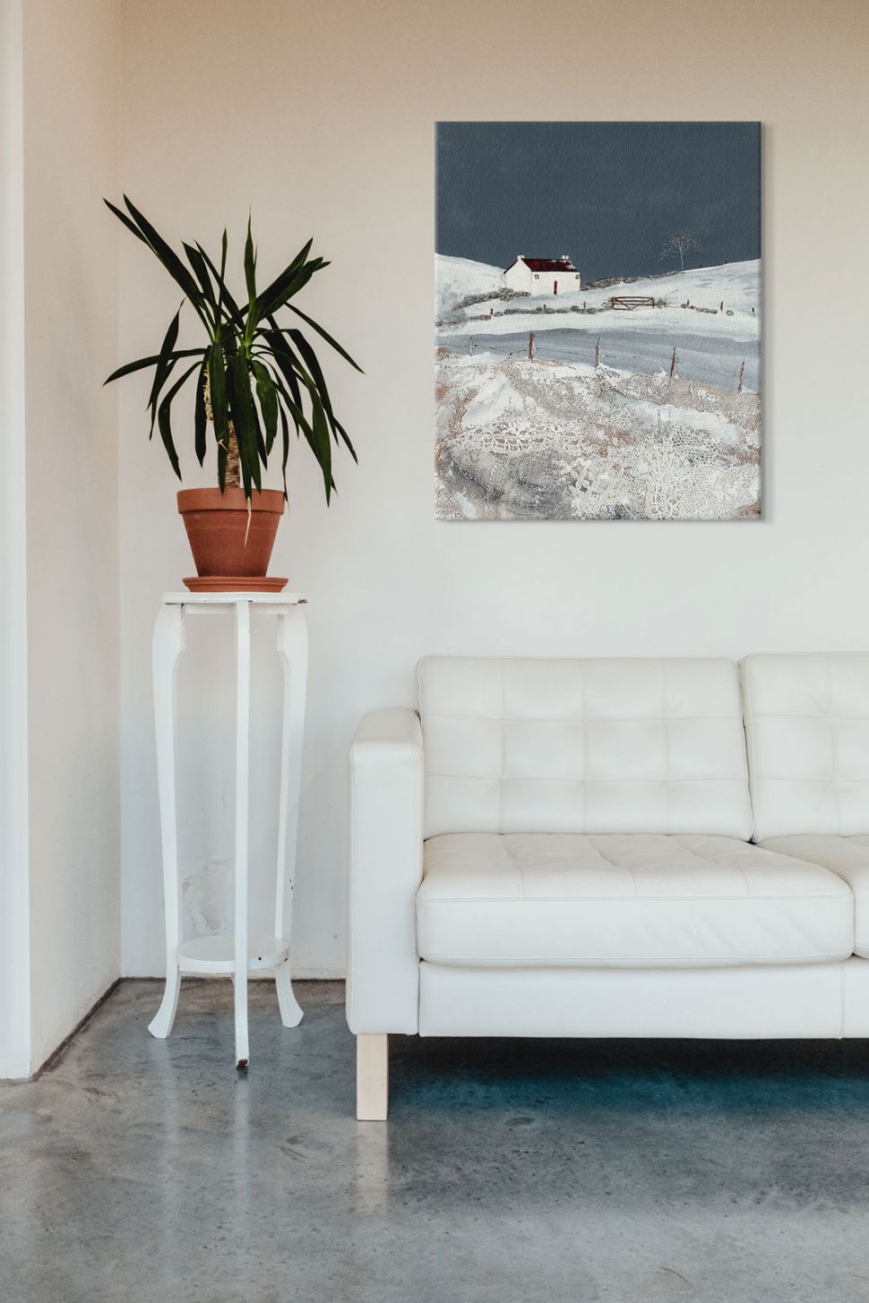 Obraz na płótnie z zimowym krajobrazem wiejskim powieszony nad białą skórzaną kanapą