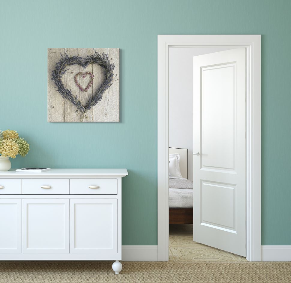 Obraz na płótnie przedstawiający lawendowe serce powieszone na niebieskiej ścianie w pokoju nad komodą z szufladami