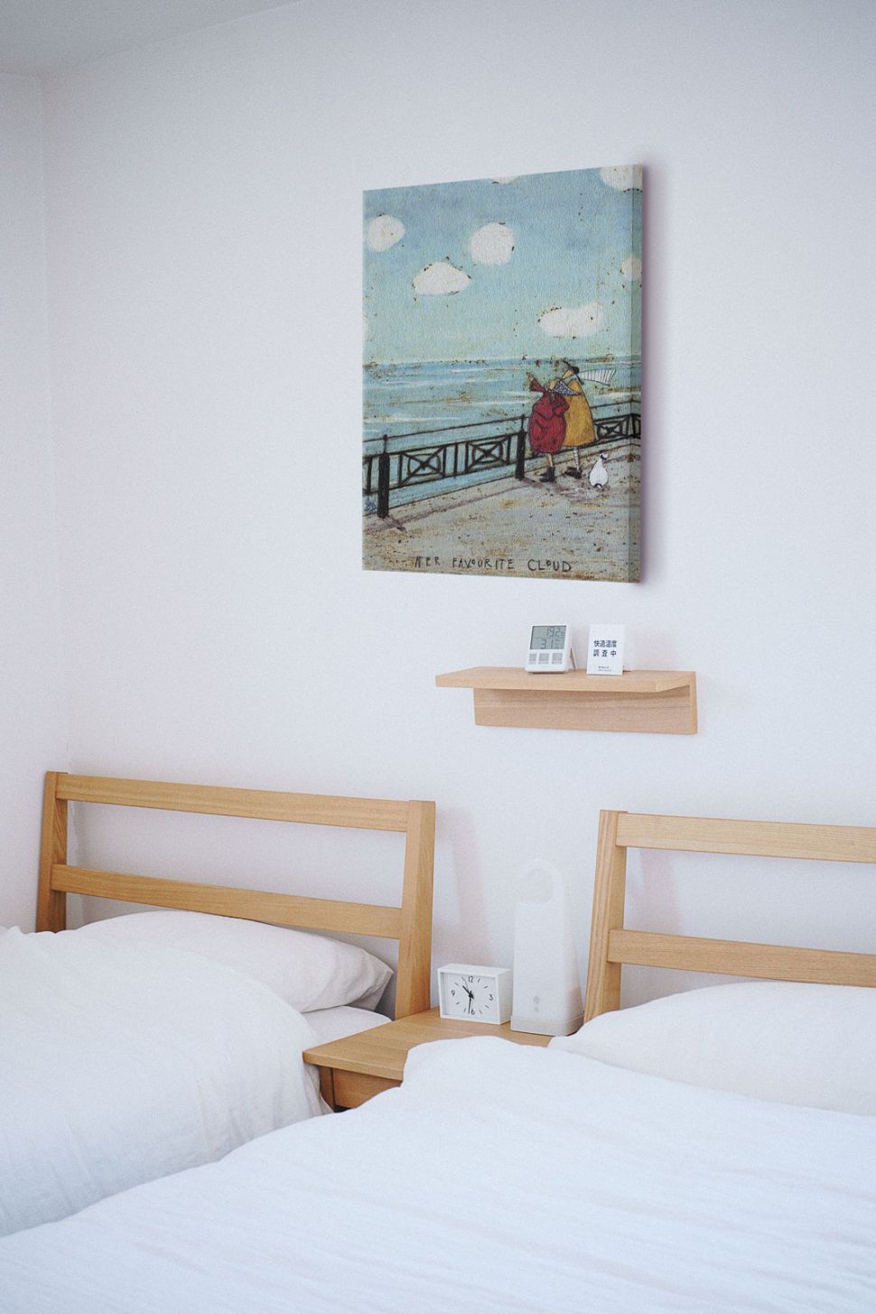 Obraz autorstwa Sam Toft powieszony w pokoju nad dwoma łóżkami z białą pościelą