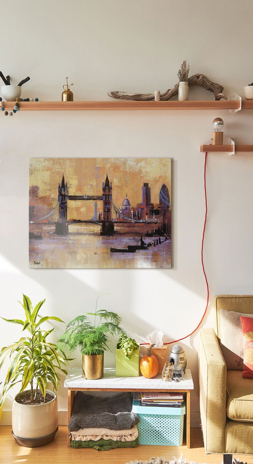 Obraz na płótnie powieszony na białej ścianie nad szafką z kwiatami w doniczce przedstawiający Tower Bridge w Londynie