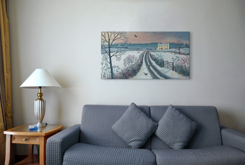 Obraz na płótnie przedstawiający zimowy krajobraz powieszony w pokoju nad szarą sofą w białe kropki