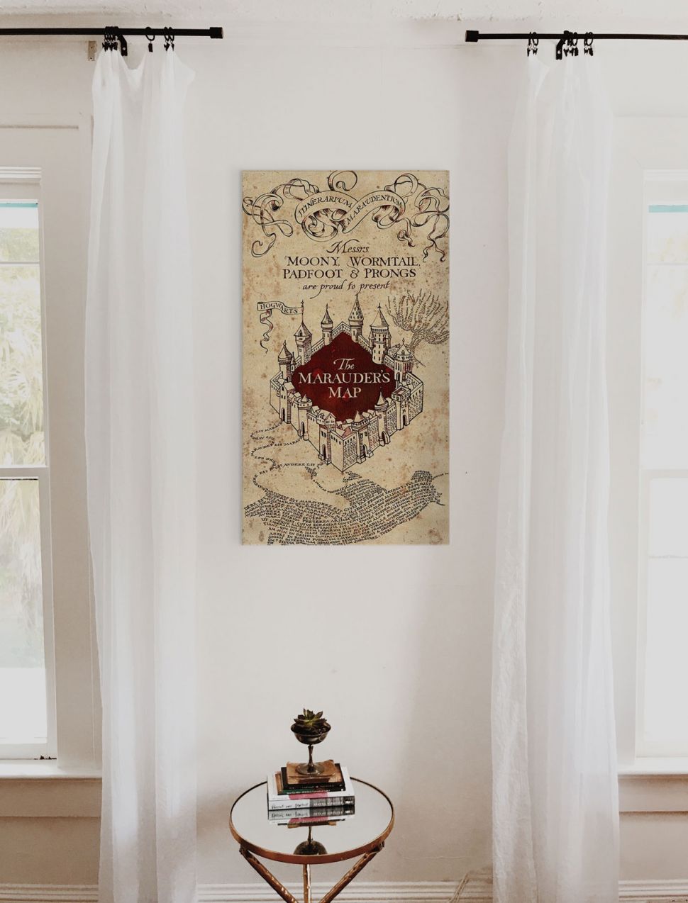 Obraz na płótnie wiszący między oknami nad małym szklanym stolikiem przedstawiający mapę Huncwotów z filmu Harry Potter