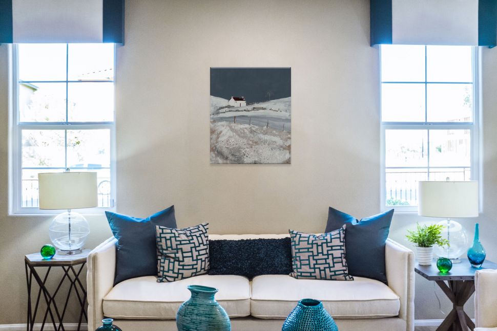 Obraz na płótnie z wiejskim zimowym pejzażem powieszony w salonie nad białą sofą