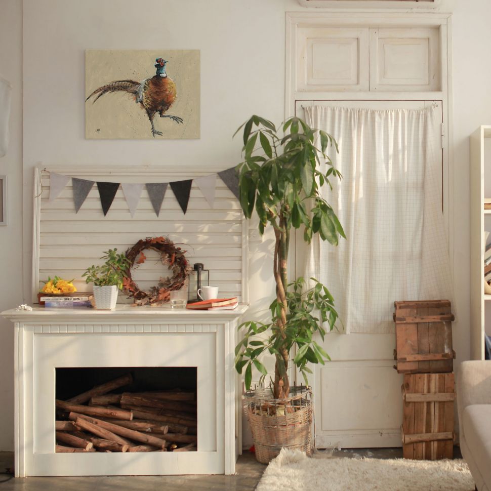 Canvas z bażantem powieszony na białej ścianie w salonie nad kominkiem
