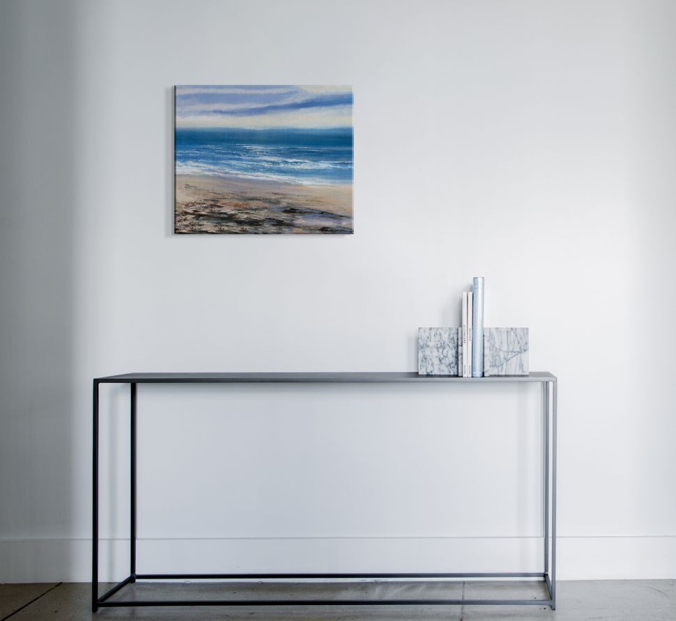 Obraz na płótnie z morskim krajobrazem powieszony na białej ścianie nad stolikiem