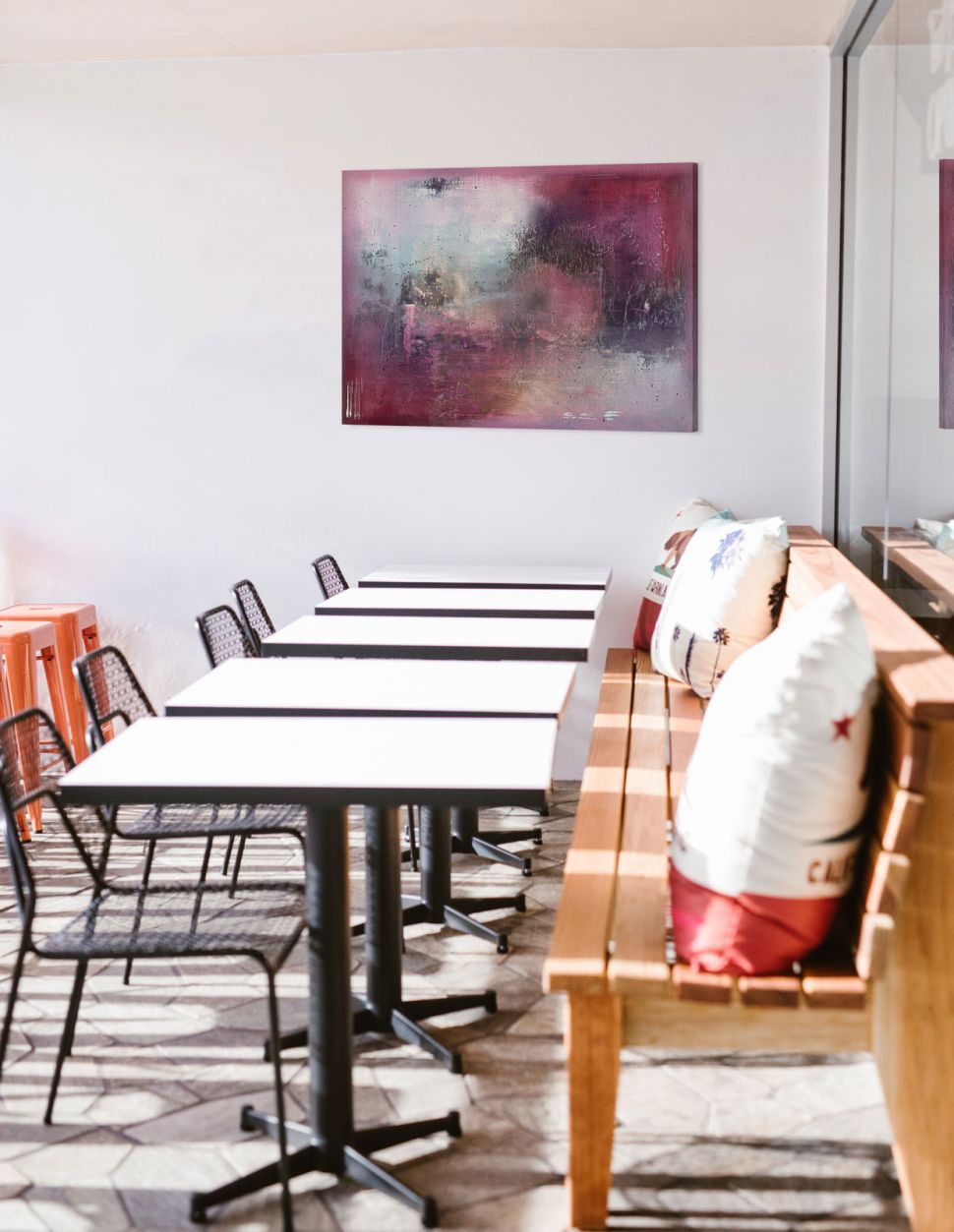 Obraz na płótnie z fioletową abstrakcją powieszony w kawiarni nad stolikiem
