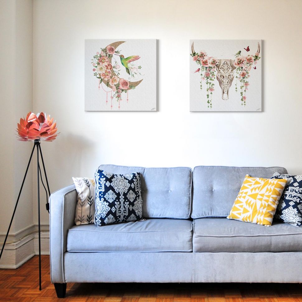 Kwadratowe canvasy autorstwa Summer Thornton powieszone nad niebieską kanapą w salonie