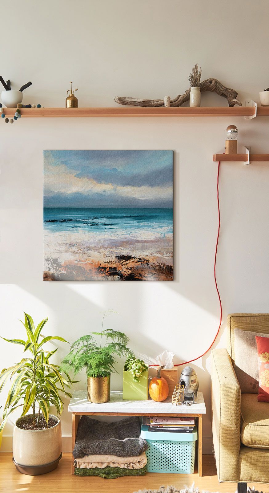 Canvas o rozmiarach 60x60 cm z widokiem na ocean wiszący w pokoju pod drewnianą półką