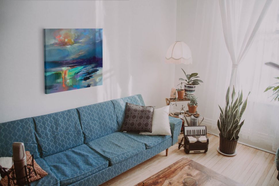 Kolorowa abstrakcja wisząca na ścianie nad niebieską kanapą