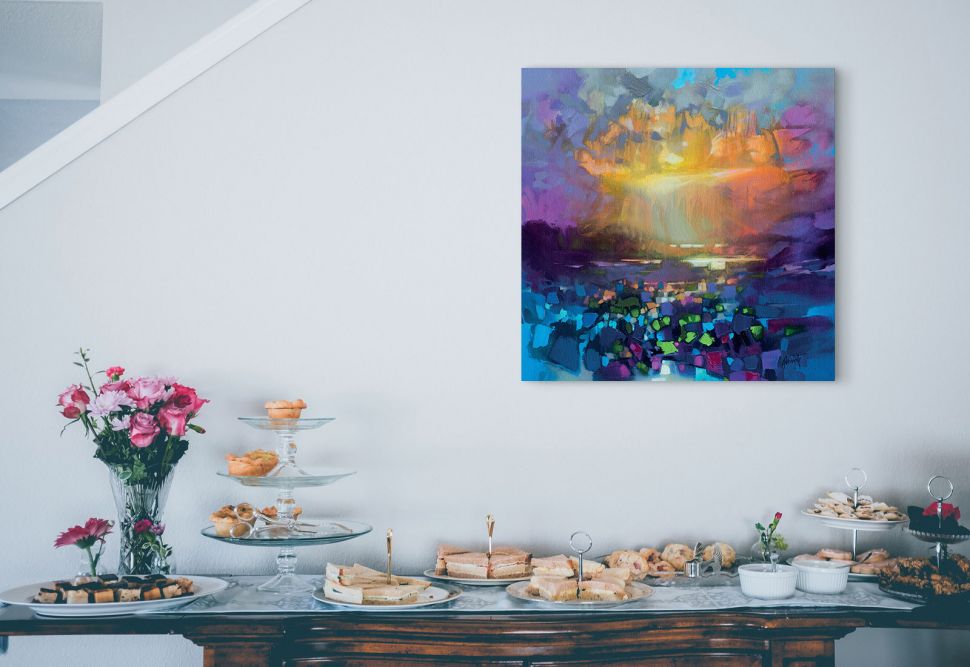 Obraz na płótnie przedstawiający zachód słońca nad polaną powieszony na białej ścianie w salonie nad komodą na której leżą ciastka