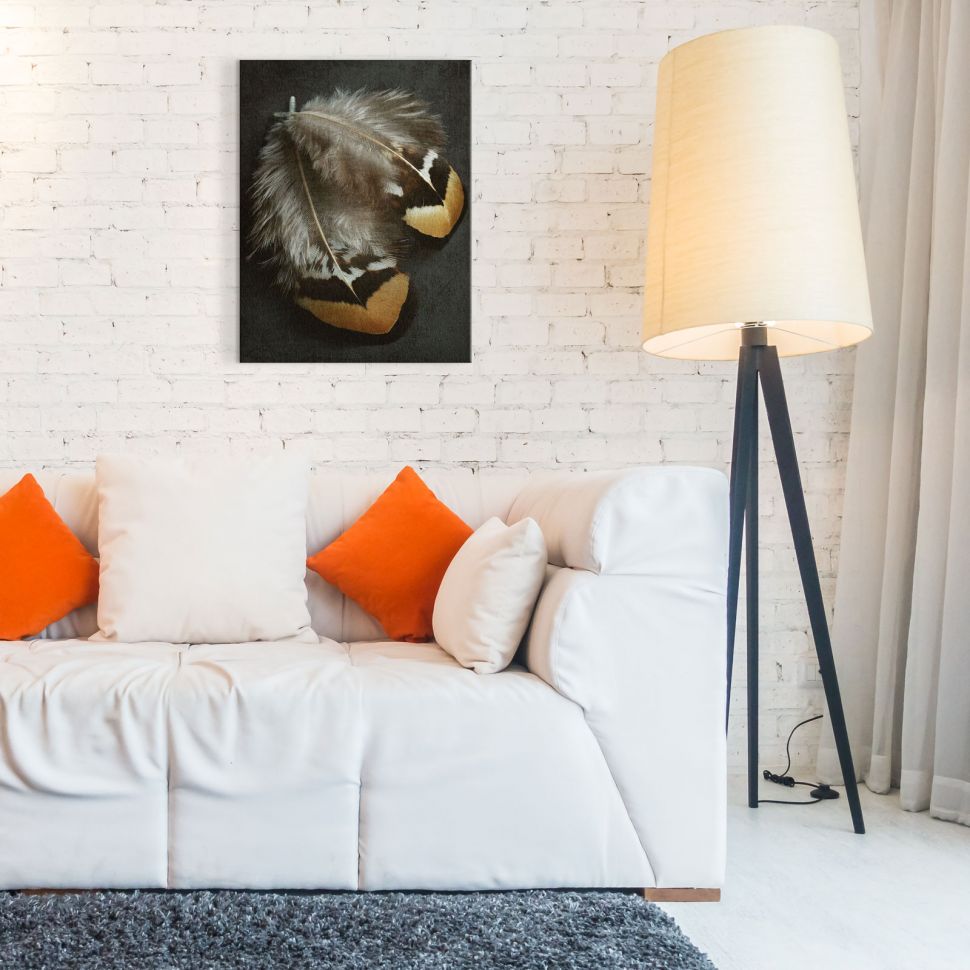 Obraz na płótnie w dwoma piórkami wiszący nad białą sofą w stylowym salonie