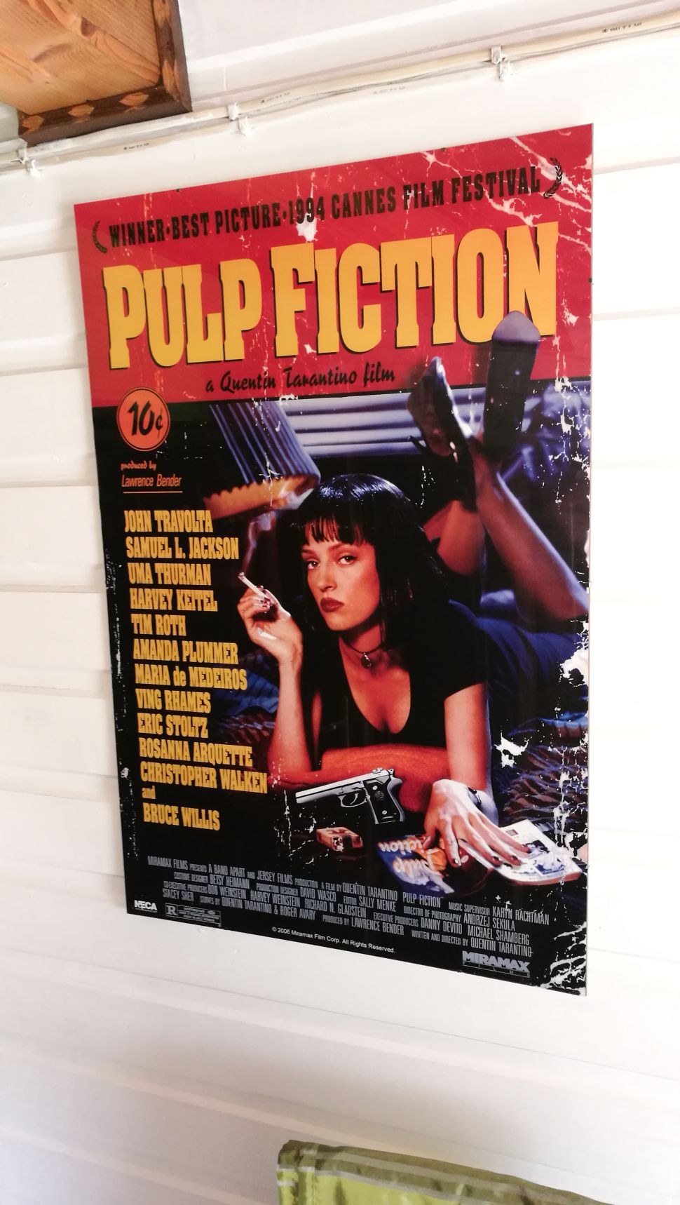 Poster z Mią Wallace z Pulp Fiction powieszony na drewnianej ścianie