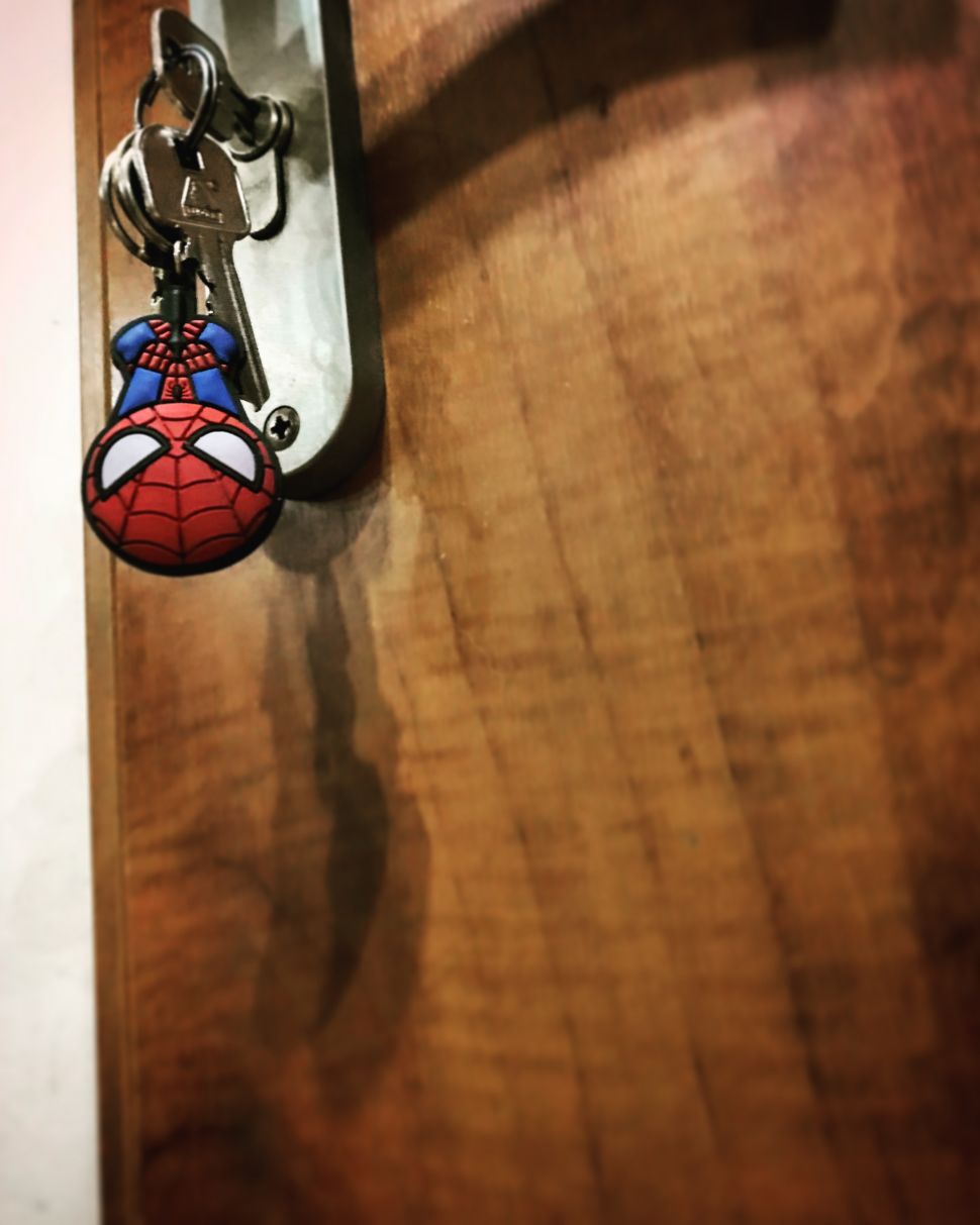 Brelok ze Spider-manem przypięty do kluczy w drzwiach