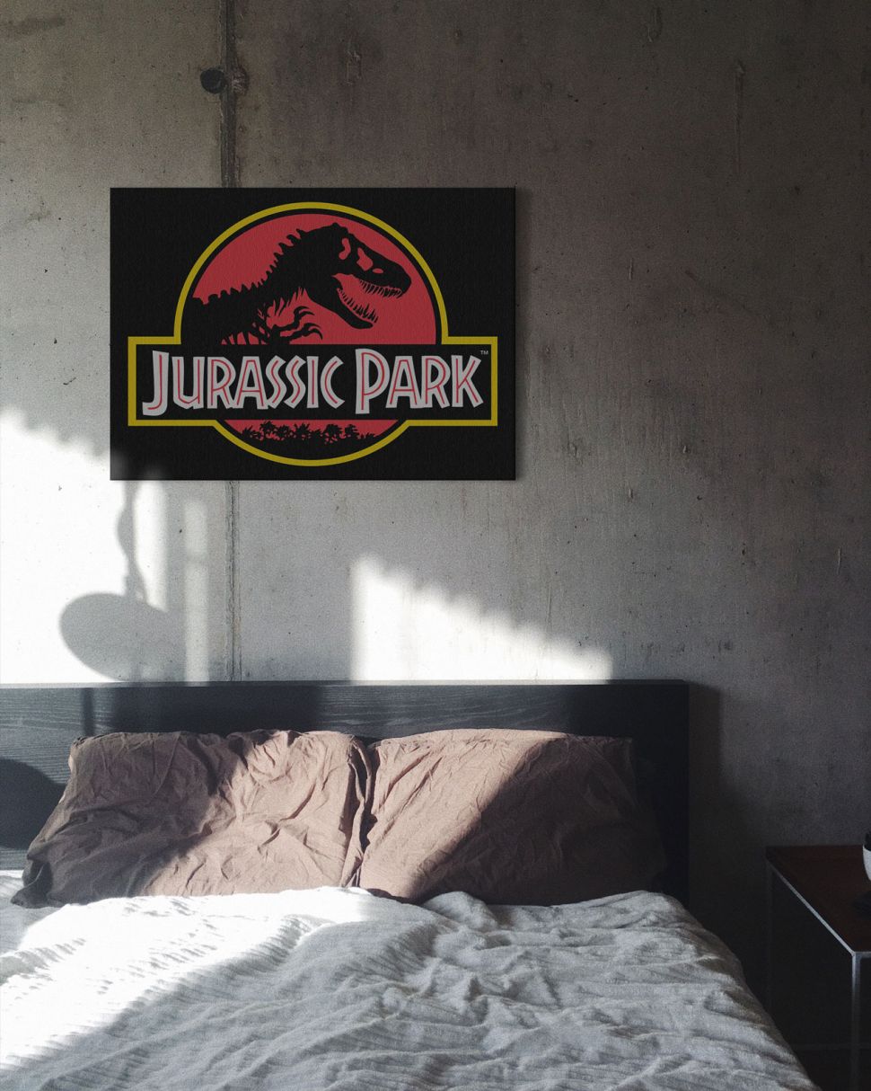 Obraz na płótnie przedstawiający logo Jurassic Park powieszony nad łóżkiem