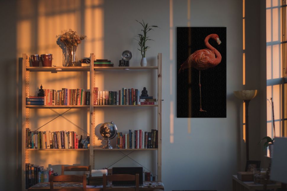 Canvas z flamingiem na czarnym tle powieszony w salonie obok półki na książki
