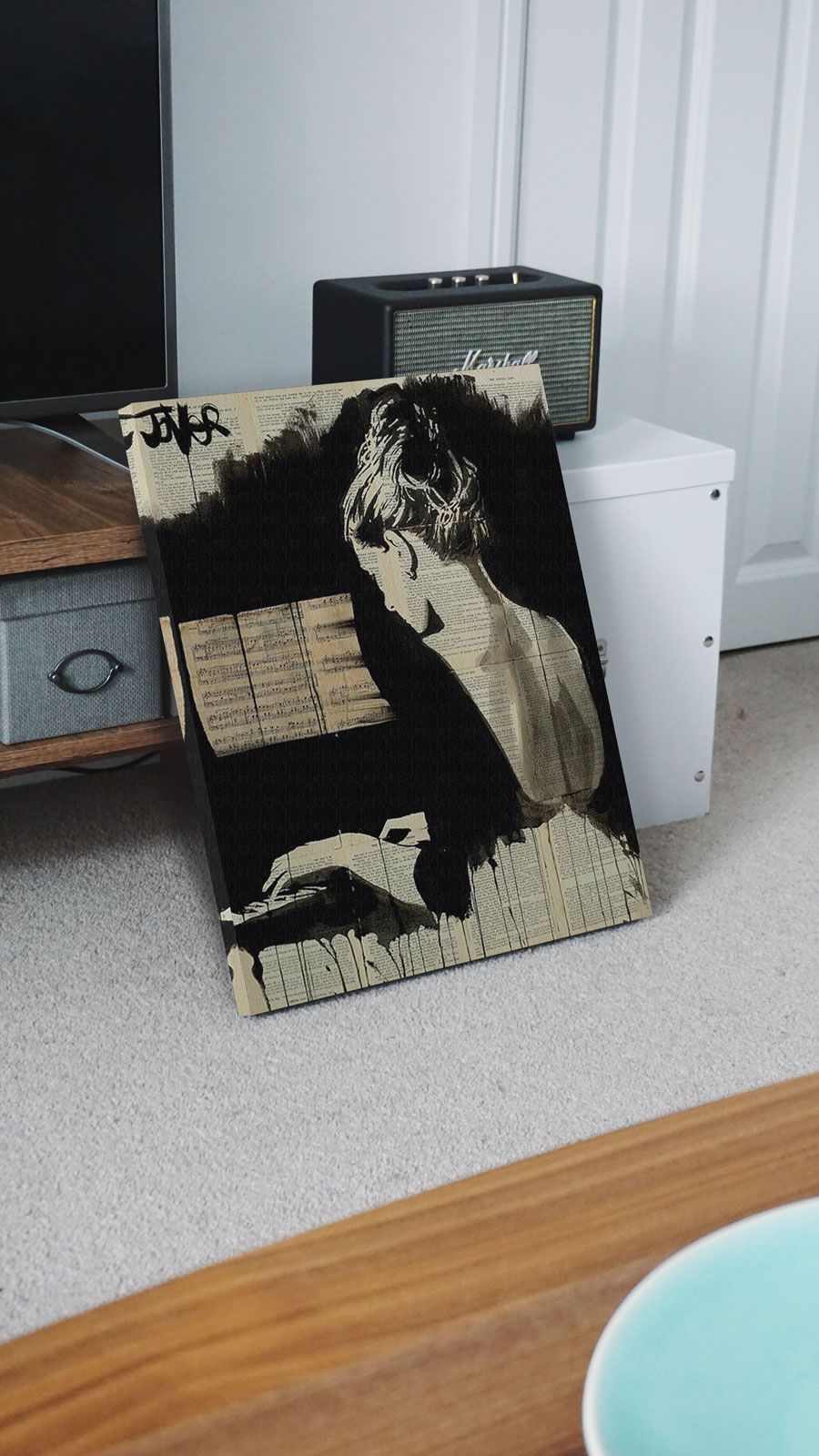 Canvas z kobietą grającą na pianinie postawiony na podłodze oparty o szafkę