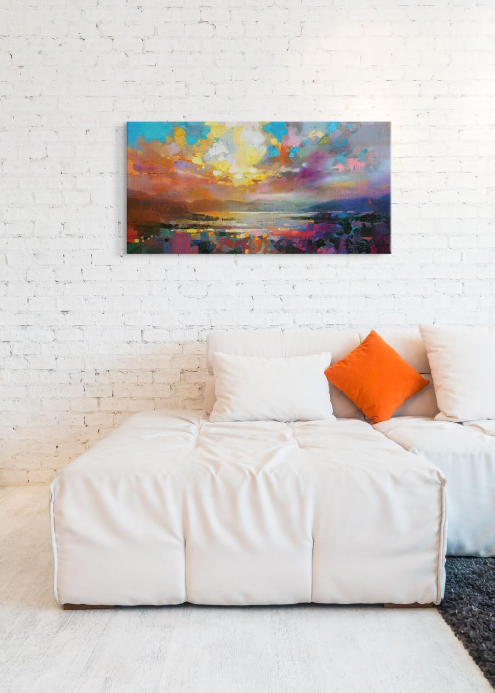 Malunek na płótnie przedstawiający kolorową abstrakcję powieszony na białej ścianie z cegły nad kanapą
