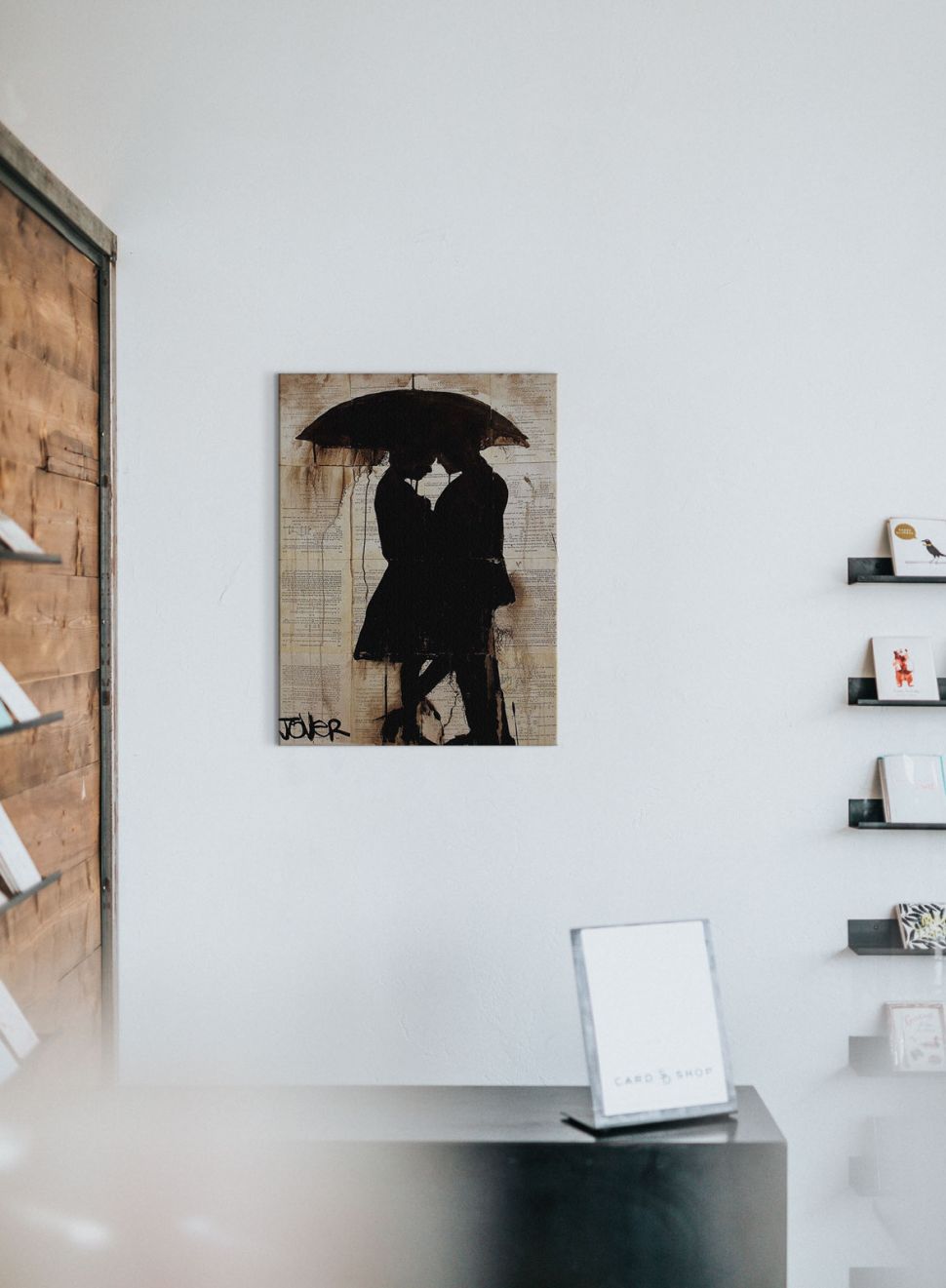 Zakochana para na obrazie autorstwa Loui Jover który powieszony jest na białej ścianie w pokoju nad biurkiem