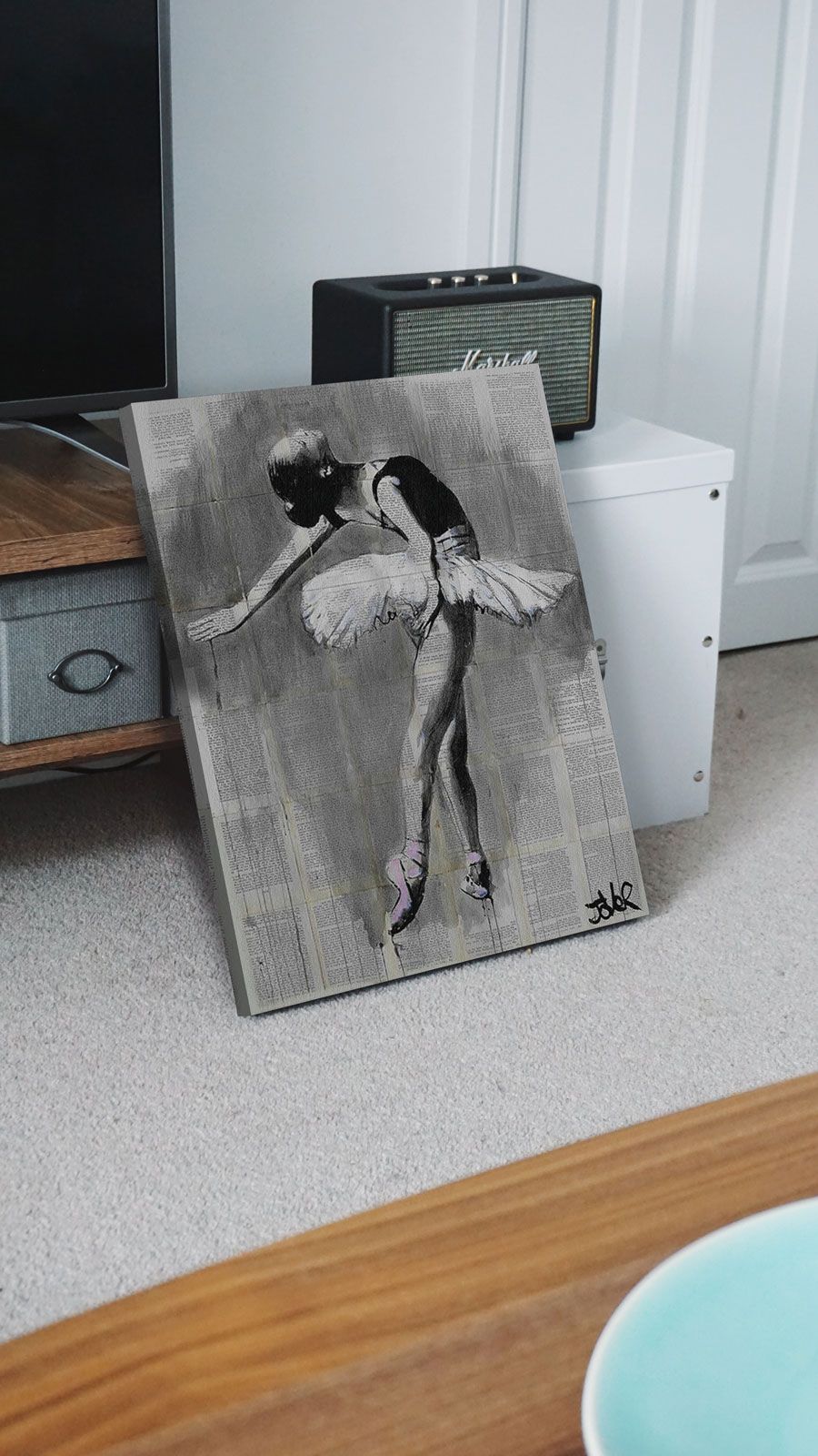 Obraz na płótnie z baletnicą postawiony obok szafki