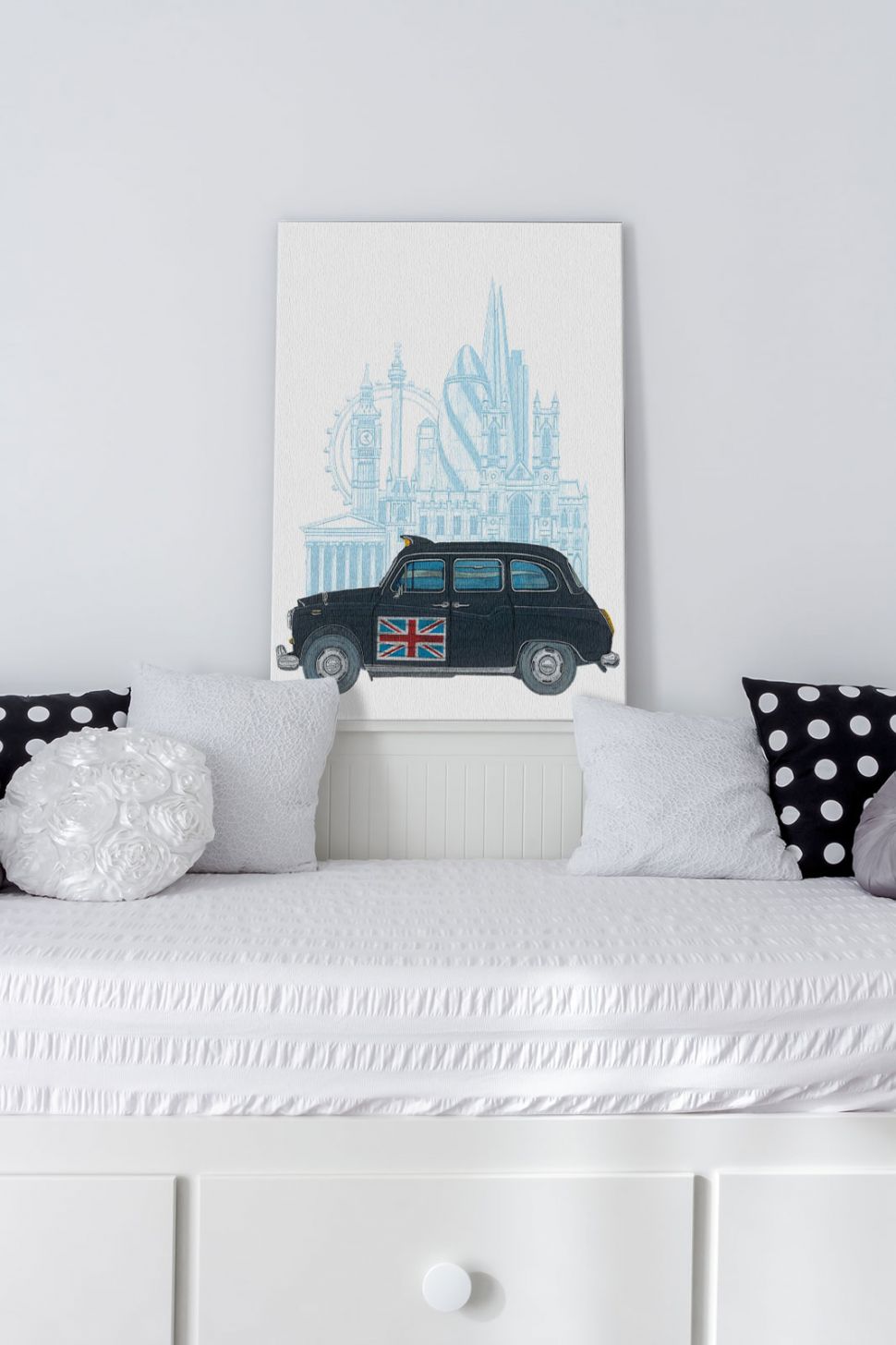 Canvas przedstawiający londyńską taksówkę postawiony na białej komodzie w pokoju