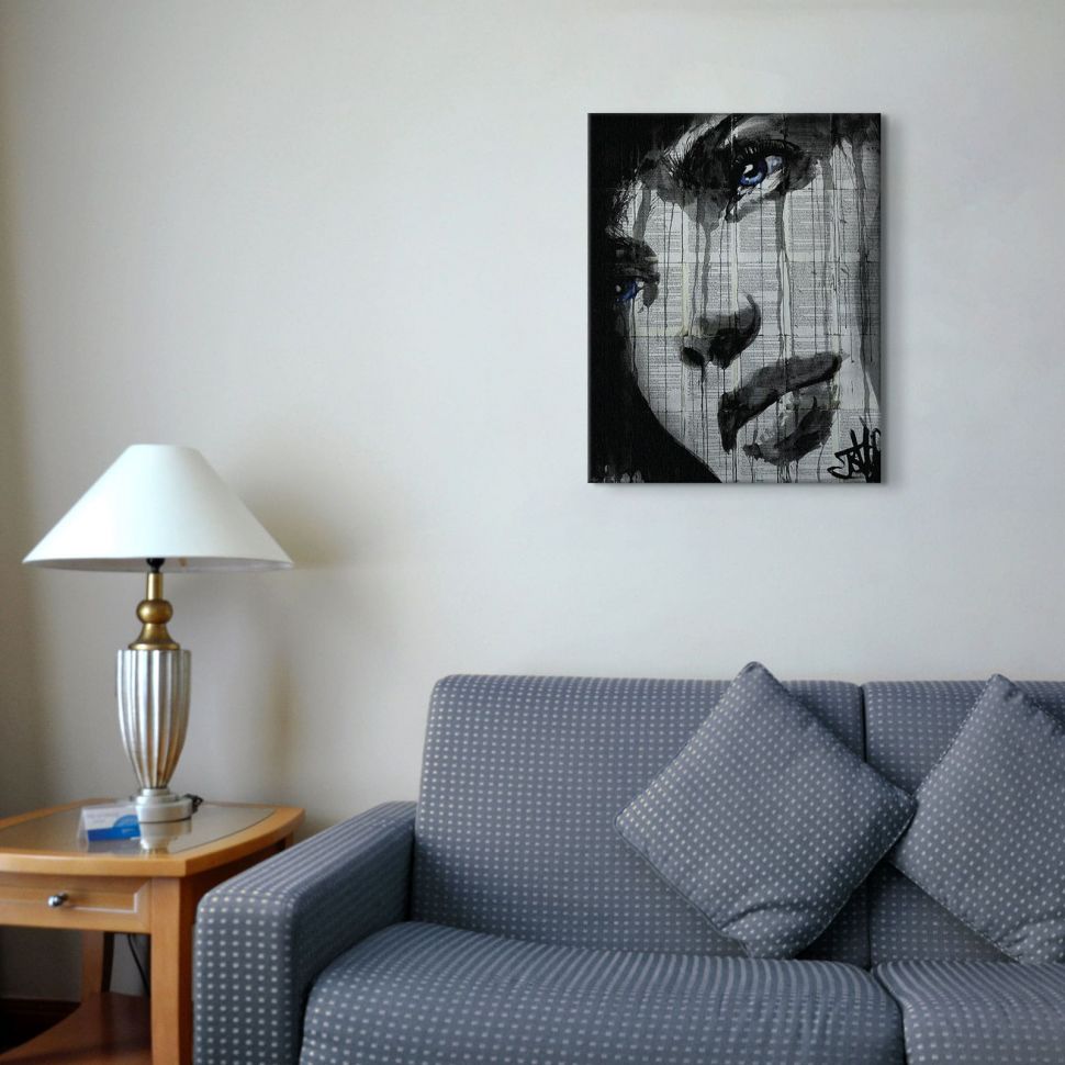 Canvas przedstawiający twarz kobiety powieszony nad szarą kanapą