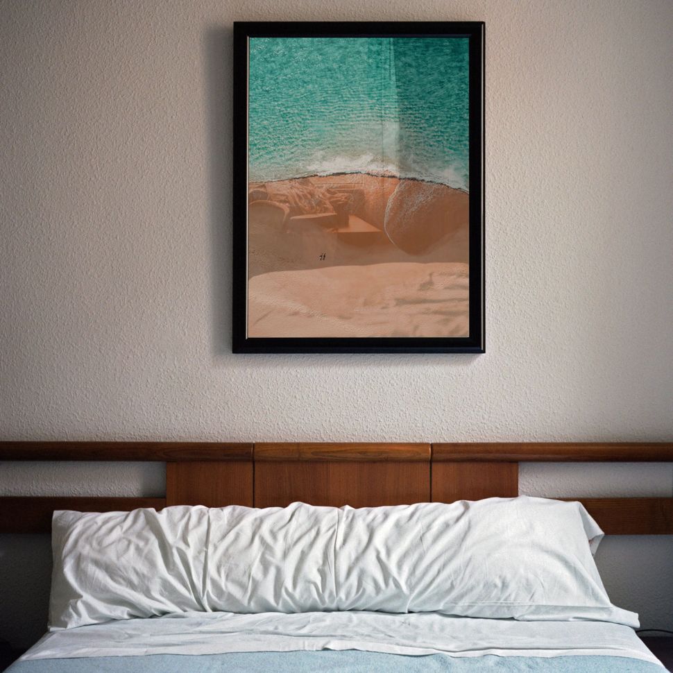 Poster Sunny Tide w czarnej ramie powieszony nad łóżkiem