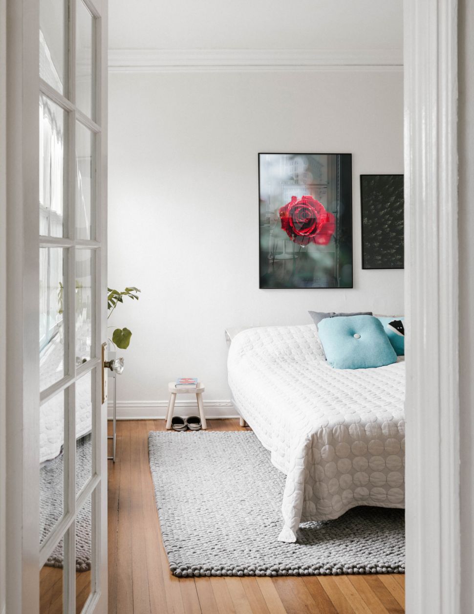 Poster Lush Rose powieszony w czarnej ramie nad łóżkiem