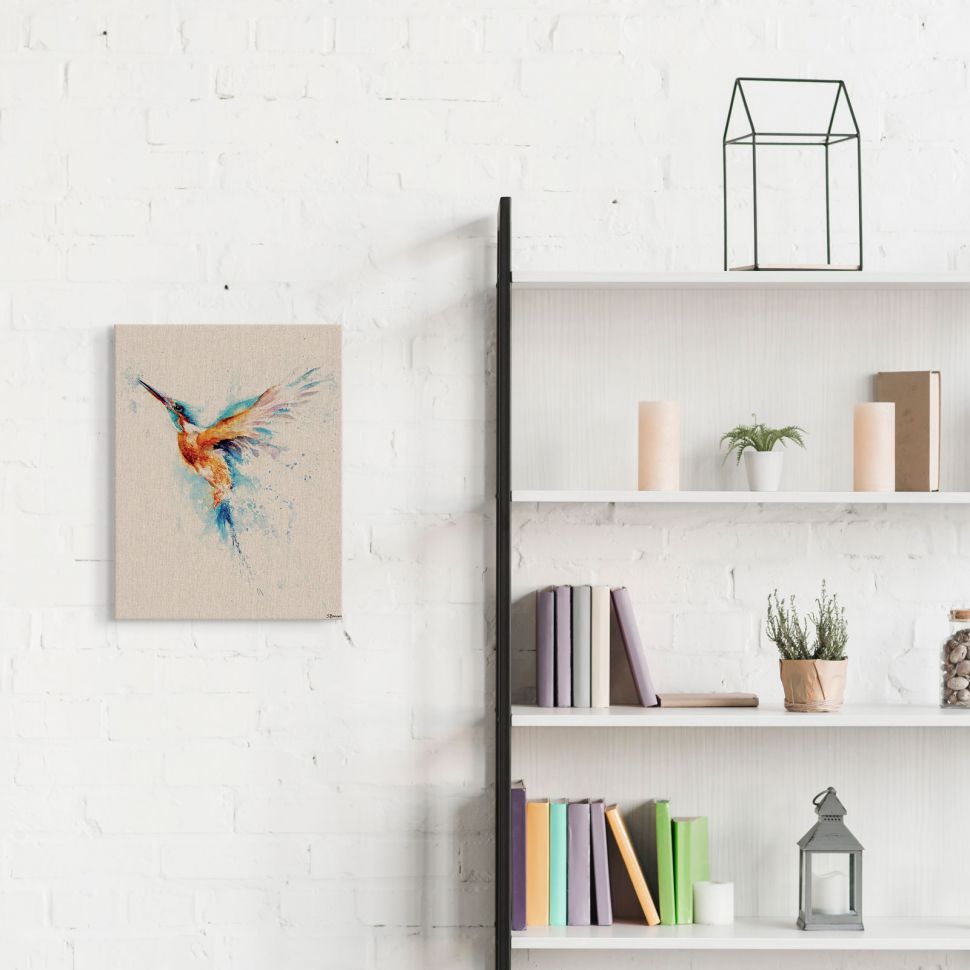 Obraz na płótnie autorstwa Jane Bannon ukazujący kolorowego kolibra powieszony w salonie obok półki z książkami