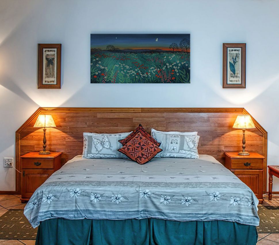Canvas namalowany przez Jo Grundy o nazwie Łąka o zmierzchu zawieszony w sypialni nad dużym łóżkiem
