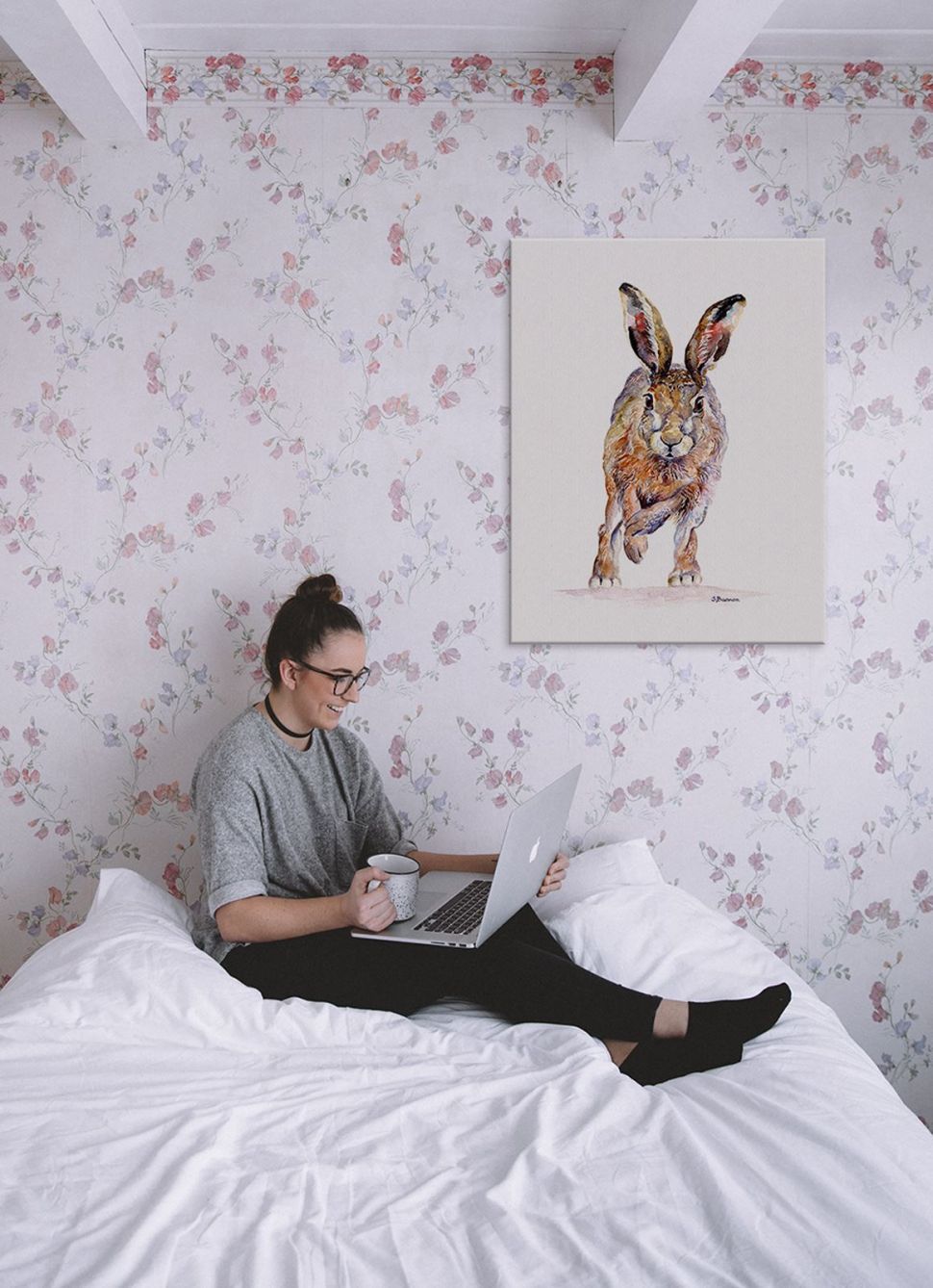 Canvas z biegnącym królikiem powieszony w sypialni nad białym łóżkiem z dziewczyną na ścianie w różowe kwiatki